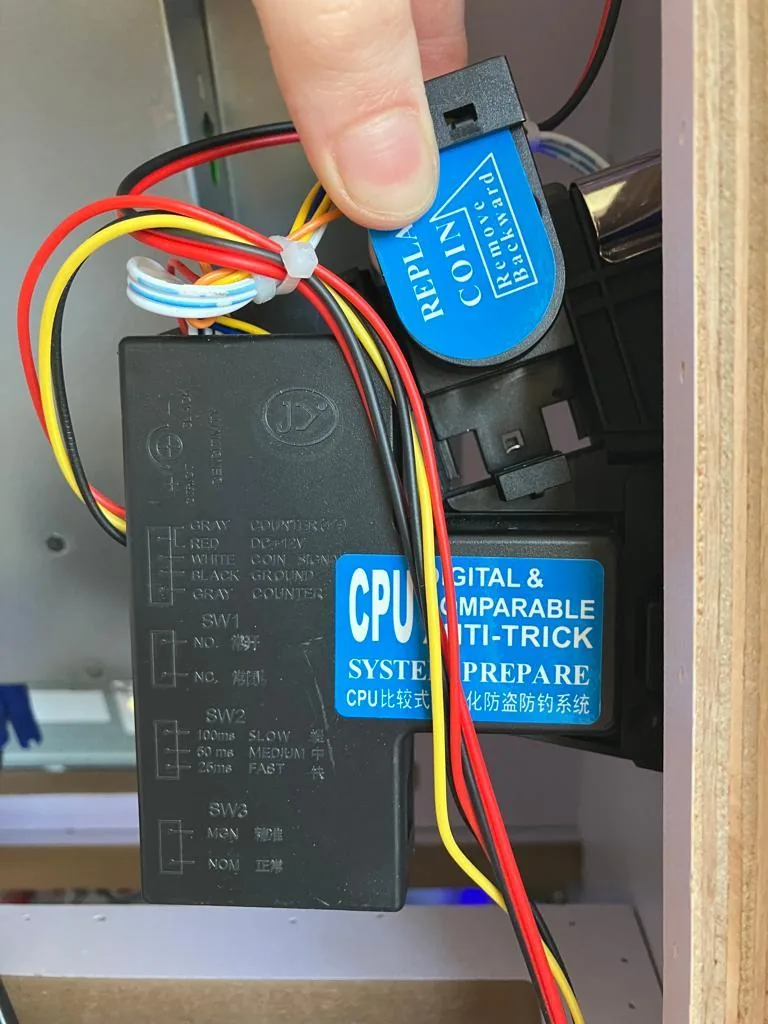 The pinball coin acceptor with the spring-loaded sample-coin slide.